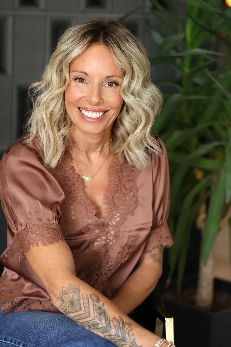 Smiling woman with soft blonde waves showing the finished look of short hair with extensions