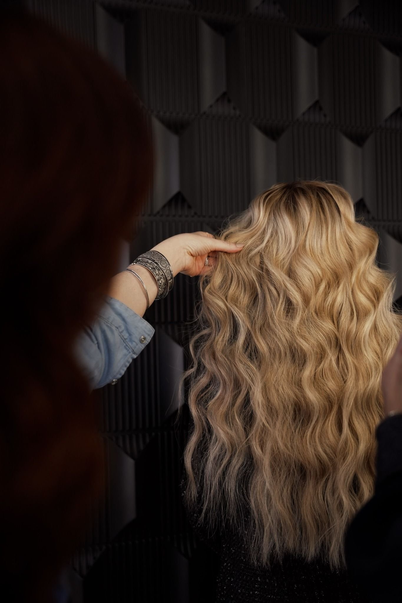 Long blonde hair extensions being professionally styled at Glam.Is.On Salon